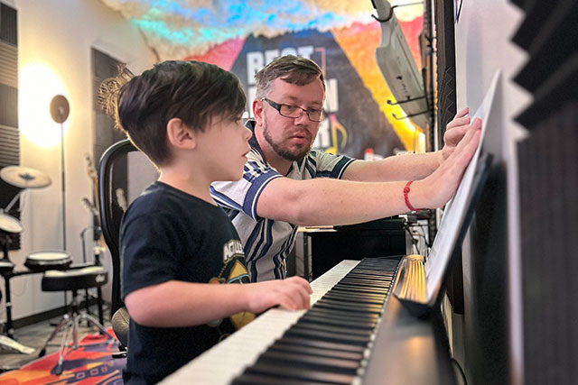 A BLE teacher helping a student at the piano