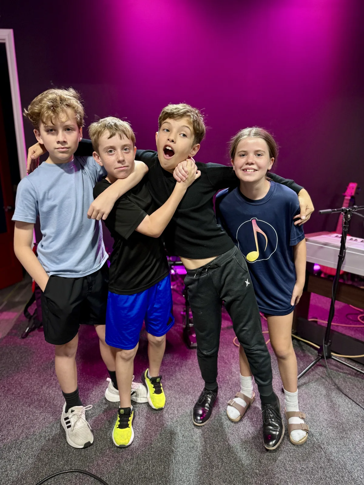 Four BLE students with their arms around each other on the studio stage