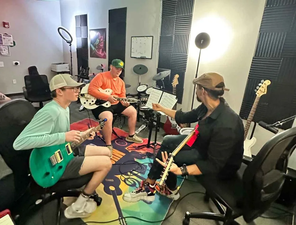 BLE instructor Nigel helping two guitar students work through music together