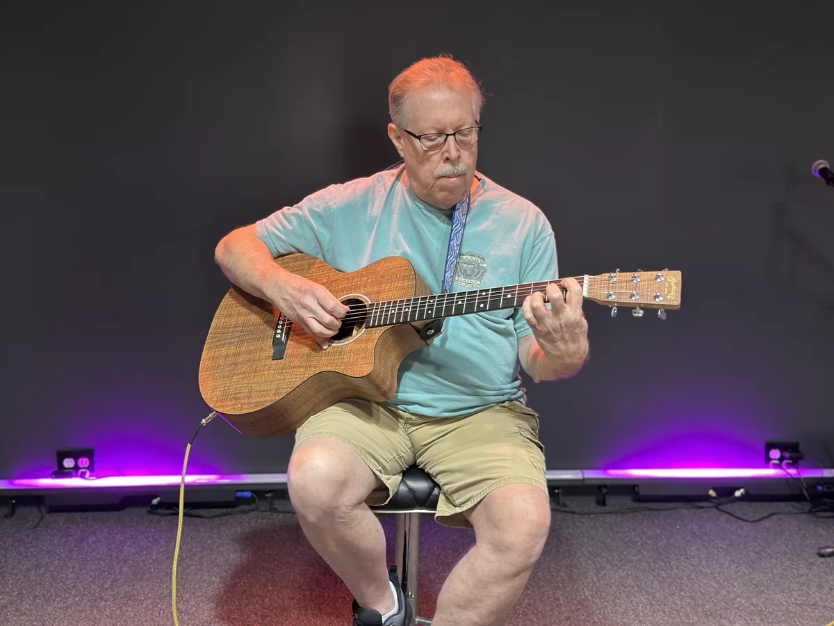An adult musician performing acoustic guitar
