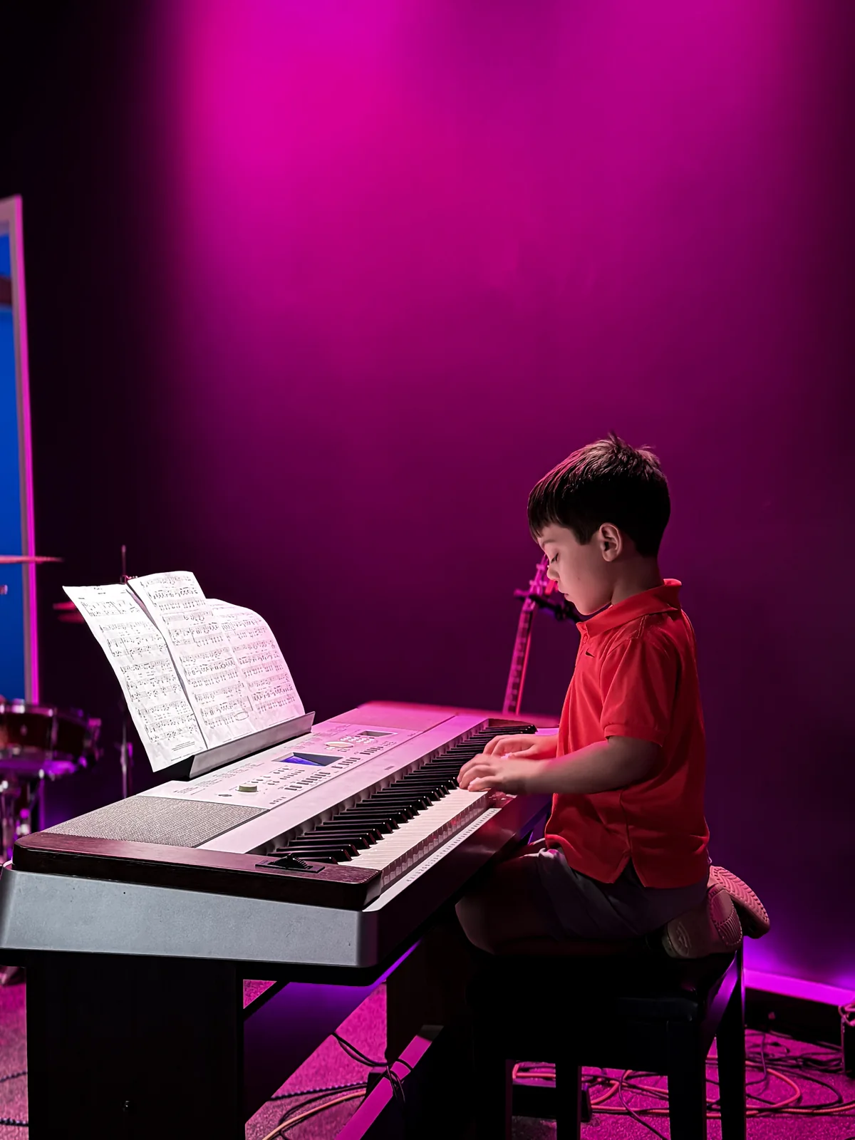 A BLE student playing keyboard on the magenta-lit stage