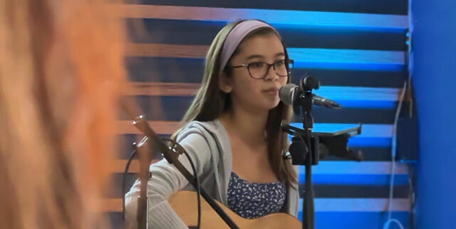 a student singing and playing on stage